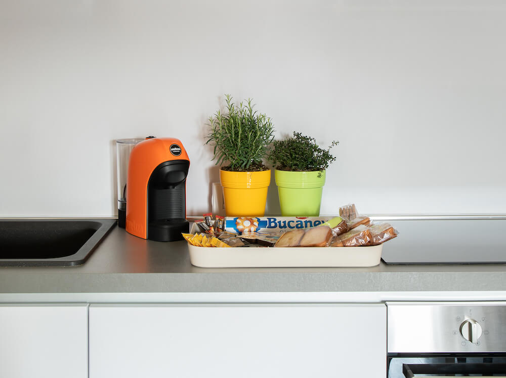 piano cucina con due vasi, macchina del caffè arancione e vassoio con biscotti