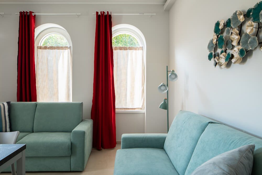 soggiorno con divani azzurri, finestre ad arco con tende rosse ed elementi decorativi