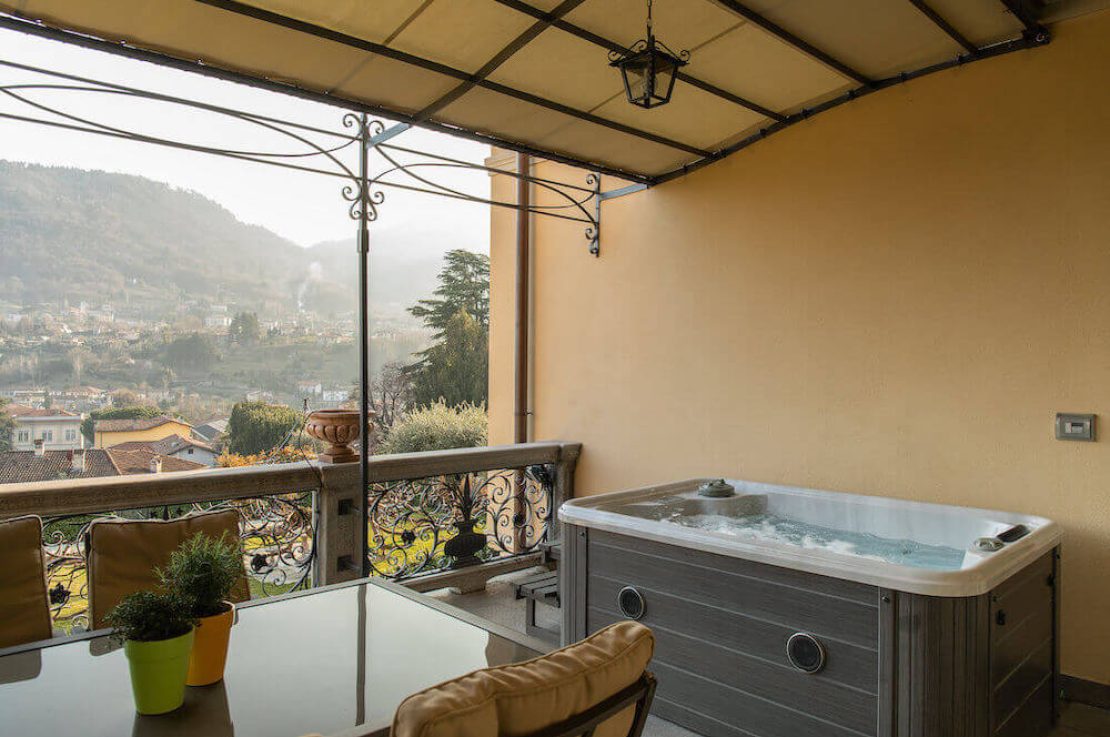 terrazza con gazebo in ferro battuto, jacuzzi, tavolo con sedie e vista su Bellagio