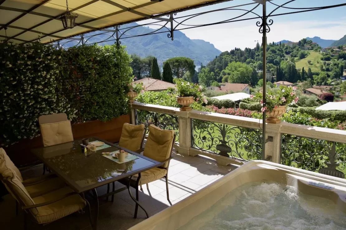 terrazza con jacuzzi, tavolo con sedie, gazebo in ferro battuto, vasi, parete con gelsomino e vista su Bellagio